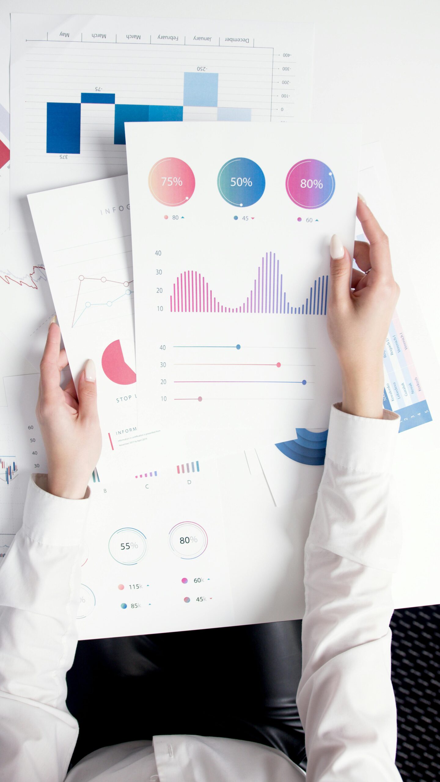 Close-up of hands analyzing colorful business data reports in an office setting.